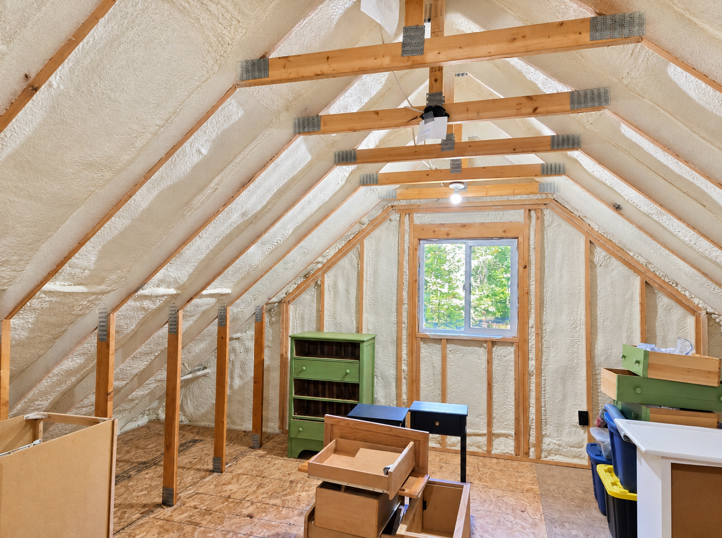 Residential attic with spray foam insulation installed between exposed roof rafters